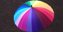 Aufgespannter Regenschirm vor einer Backsteinwand als Sinnbild für die Familienholding als Dachgesellschaft